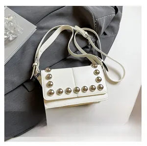 Detailed view of a white leather crossbody bag with silver rivets and phone size reference