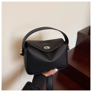 Détail d'un mini sac en cuir litchi noir avec fermoir rotatif argenté et poignée