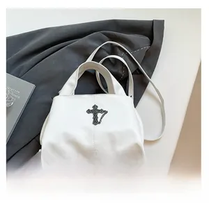 Detail of white lychee-patterned bag featuring a gothic cross pendant and metal chains