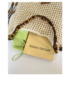 Detail of hand-woven beige tote with beaded handles showing storage for a book and umbrella