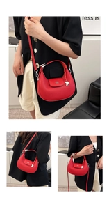 Dettaglio borsa a mezzaluna in pelle martellata rossa con logo e ciondolo a cuore
