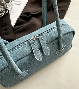 Detail view of denim shoulder bag featuring high-quality silver double zippers and texture