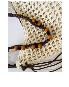 Detail of hollow diamond mesh woven bag with dark brown beaded handle and wooden beads