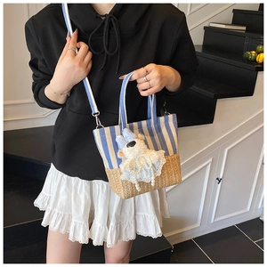 Blue striped canvas bucket bag with woven straw base shown on model in a modern interior