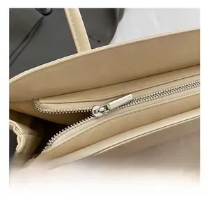 Détail de la fermeture éclair argentée et texture cuir du sac bowling beige