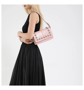 Detail of pink glossy leather shoulder bag featuring large silver dome rivet embellishments