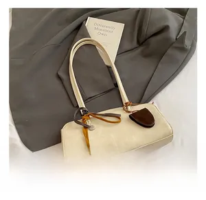 Détail du sac bowling crème avec fine bandoulière et pendentif en cuir marron