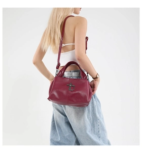 Close-up of burgundy lychee-textured leather bag with vintage silver cross hardware