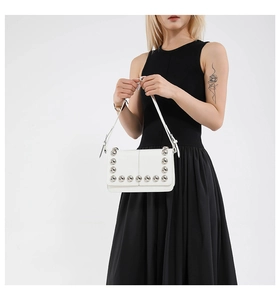 Detail of white punk style handbag featuring large silver studs on a smooth leather flap