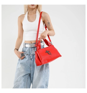 Detail of red leather tote bag featuring vintage metal cross pendant and chain detail