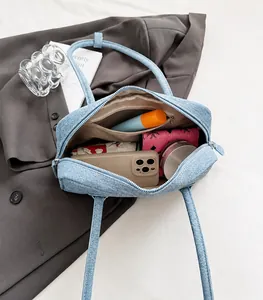 Detailed interior of a blue denim shoulder bag showing spacious storage and inner pocket
