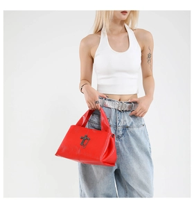 Dettaglio di borsa punk rossa in pelle con catena metallica a croce vintage in mano
