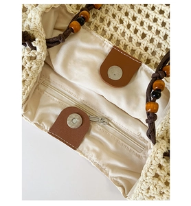 Detail of straw tote bag interior with satin lining, zip pocket and magnetic buckle closure