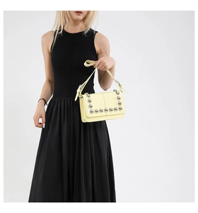 Detail of yellow punk crossbody bag with silver rivet studs on shoulder of model