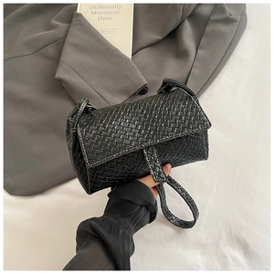 Detail of black woven shoulder bag with white contrast stitching and minimalist flap