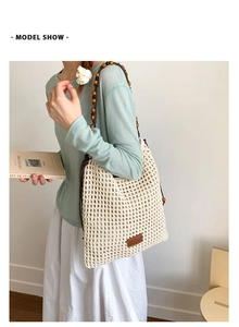 Detail of hand-woven beige straw tote bag with retro wooden bead straps and leather patch