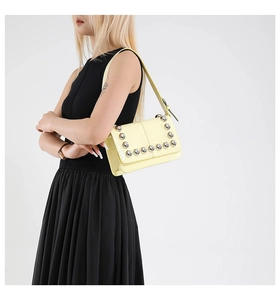 Detail of yellow biker style shoulder bag featuring silver spherical stud embellishments