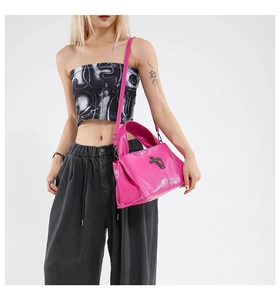 Detail of pink glossy shoulder bag with metallic cross and stud accents