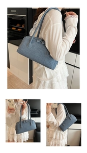 Detailed view of washed blue denim texture and stitching on the rectangular shoulder bag