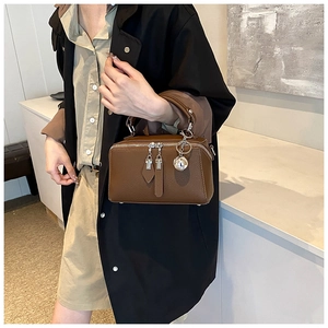 Détail du sac Boston en cuir marron foncé à grain de litchi avec doubles fermetures éclair