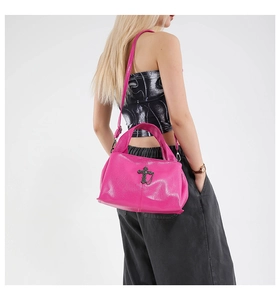 Detail of bright pink leather tote bag featuring vintage cross metal and chain ornament