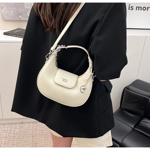 Dettaglio della borsa a mezzaluna beige in pelle martellata con ciondolo a cuore