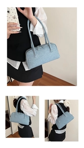 Close-up of light blue denim Boston bag showing fabric texture and shoulder strap details
