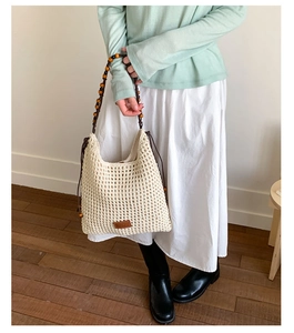Detail of hand-woven cotton bucket bag with beaded shoulder strap and leather patch