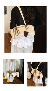 Détail d'un sac bowling blanc crème avec des breloques en cuir marron et cordons colorés