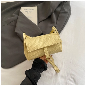 Detailed view of yellow woven faux leather texture and flap design on a crossbody bag