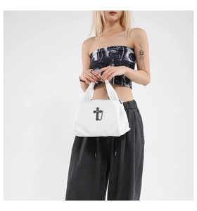 Detail view of a white leather punk crossbody bag featuring black gothic cross and chain