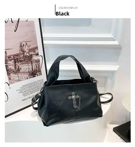 Dettaglio borsa gotica nera con pendente a croce argento e catene metalliche