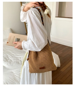 Detail of woven straw bag with wooden beads and leather patch on white dress