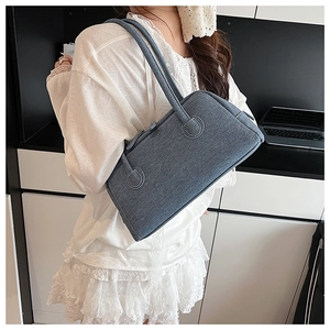 Detailed close-up of blue denim Boston bag texture and double handle design on shoulder