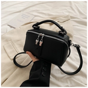 Detailed macro of black litchi grain leather texture and silver dual zippers on handbag