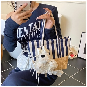 Detail of striped beach tote bag featuring a plush dog charm and woven cord handles