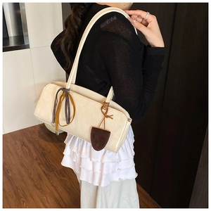 Détail du sac baguette en cuir crème avec des cordes nouées colorées et un pendentif