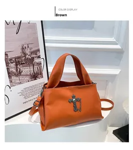 Dettaglio macro della borsa in pelle marrone con croce metallica vintage e borchie