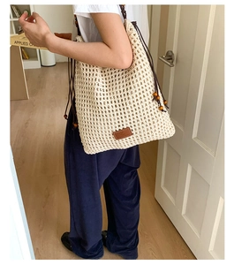 Detail of hand-woven beige tote bag with hollow mesh texture and brown drawstring closure