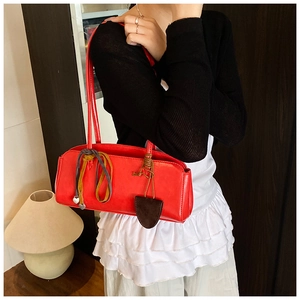 Détail du sac à bandoulière en similicuir rouge avec breloque cœur et cordon coloré