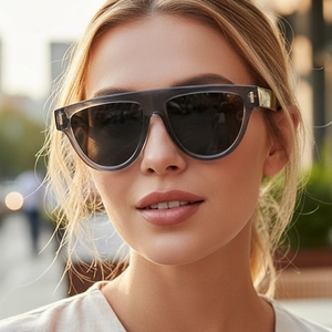 Oversized flat-top smoke grey sunglasses with dark lenses on female model outdoors