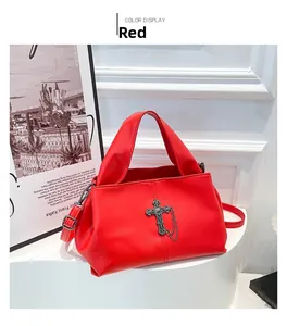 Dettaglio borsa in pelle rossa a grana con croce metallica vintage e catena decorativa