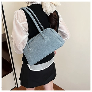 Detail of light blue denim Boston bag texture and slim shoulder straps on a model