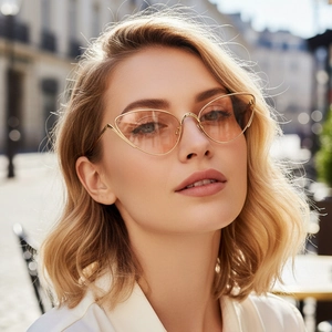 Vintage cat-eye sunglasses with gold metal frame and tinted orange lenses on a model