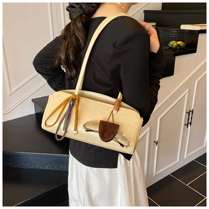 Détail du sac à bandoulière beige avec porte-lunettes en daim marron et breloque en cœur
