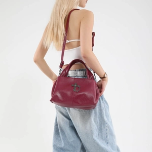 Burgundy tote bag with gothic cross ornament shown on a model from a side view angle