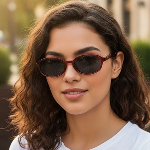 Lunettes de soleil ovales rétro avec monture rouge translucide portées par un mannequin