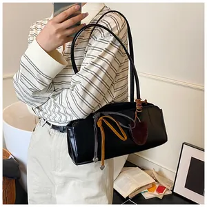 Gros plan du sac à bandoulière rétro noir avec rubans décoratifs et pendentif cœur