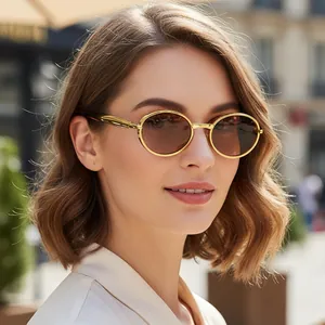 Détail de lunettes de soleil ovales dorées avec double pont et verres marron sur modèle