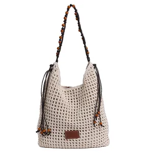 Beige crochet woven tote bag with wooden bead shoulder straps and fringe details